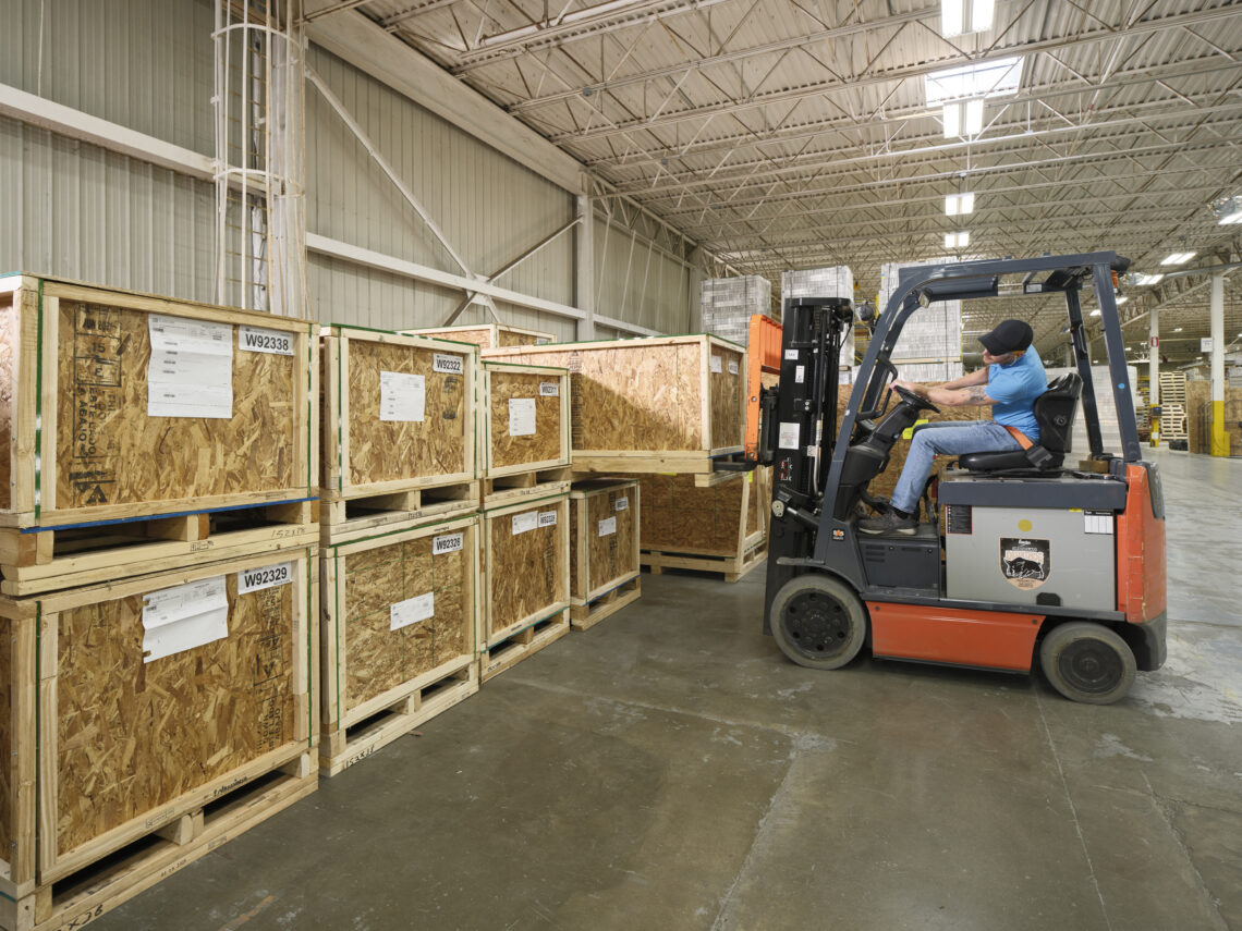 Employee on a forklift moving shipping crates in the loading docks